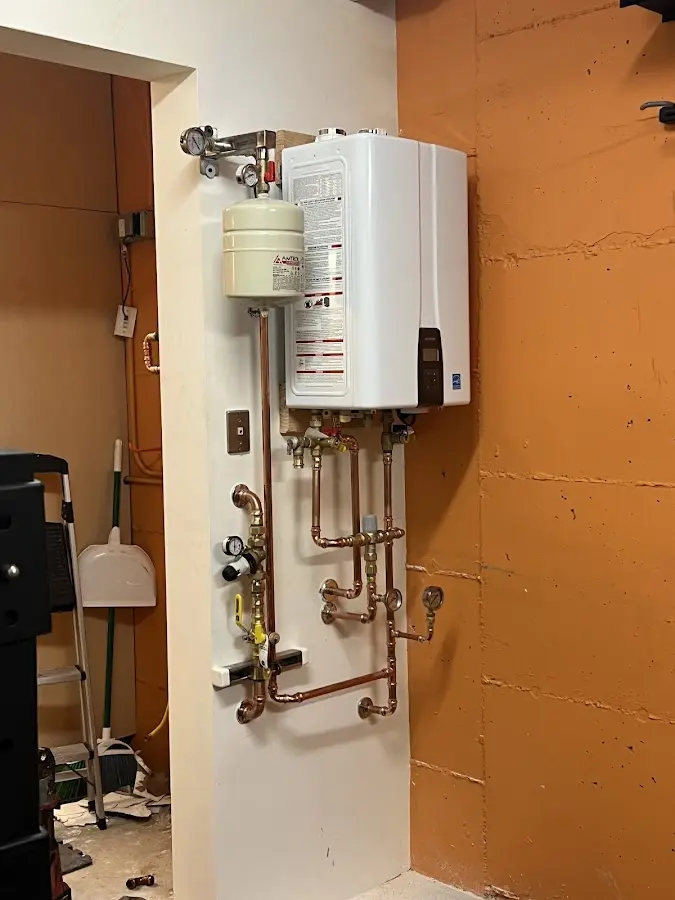 Plumbing technician inspecting water heater connections in Caernarvon